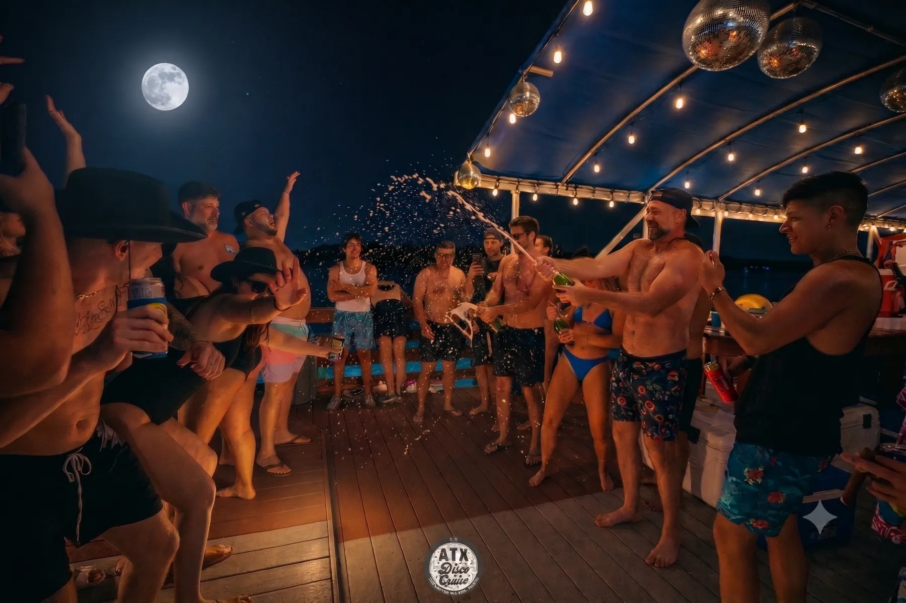 Champagne-spray celebration on a night cruise under a full moon