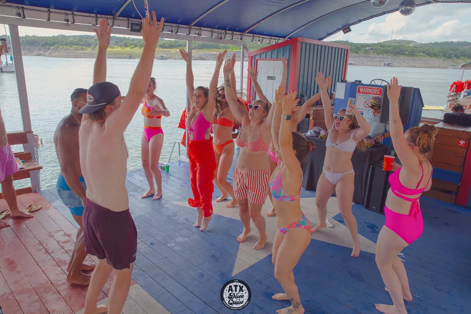 A packed crowd dancing with hands up on a Lake Travis party cruise